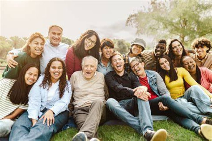 a group of people sitting next to each other on top of a grass covered