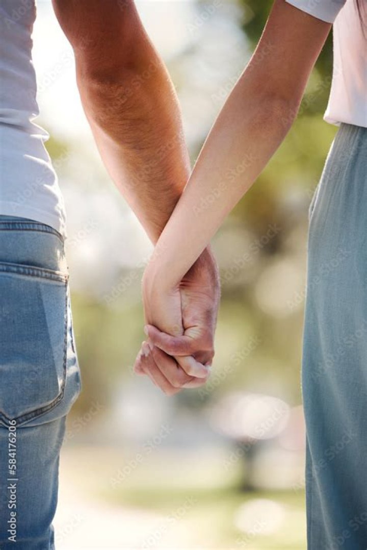 a man and woman holding each other's hands while standing in front of trees