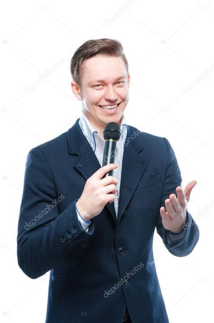 a man holding a microphone up to his mouth while standing in front of a
