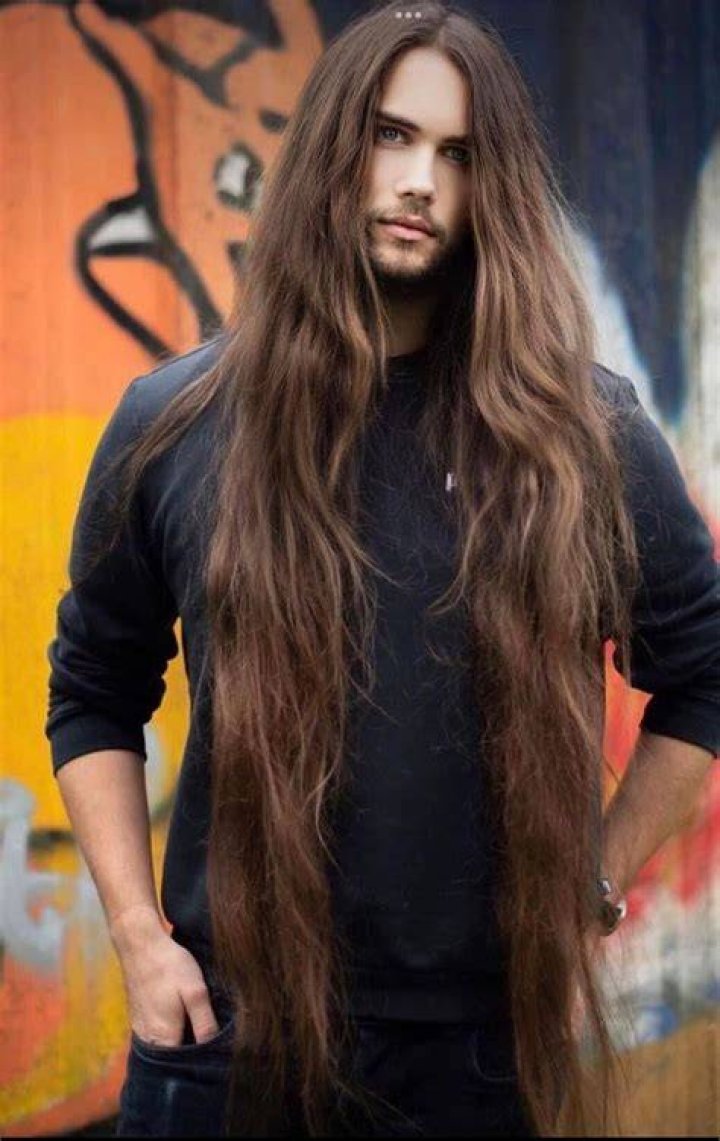 a man with long hair and beard wearing a leather jacket is looking at