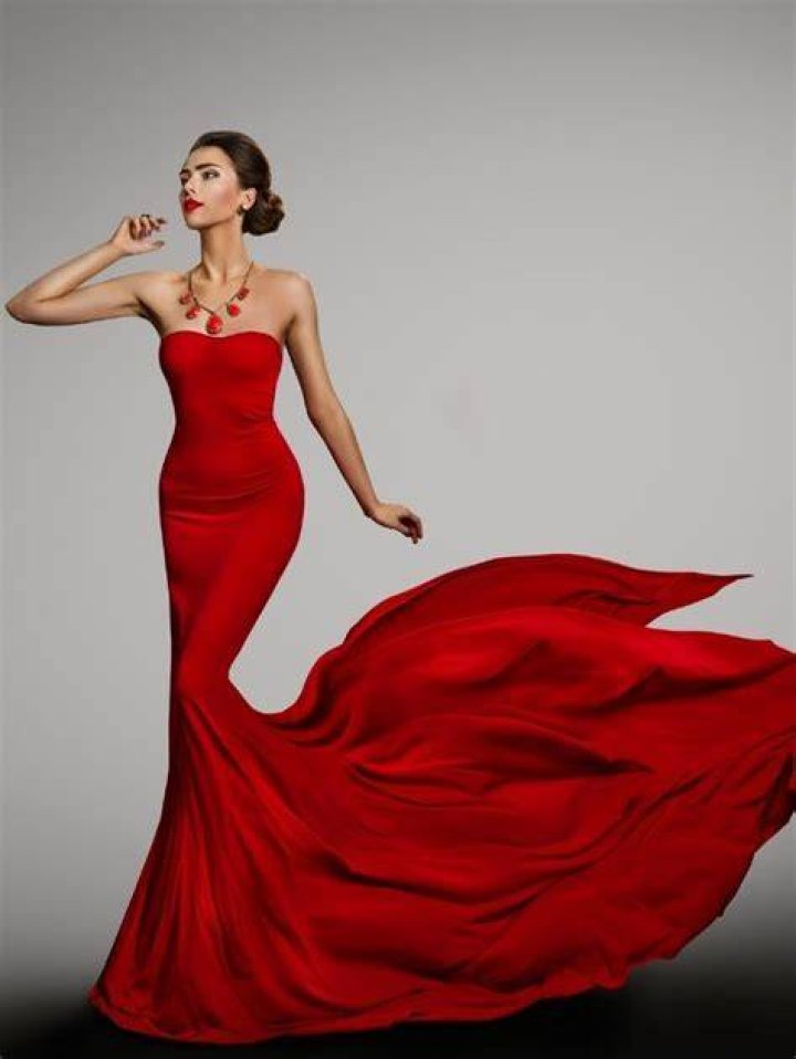 a woman in a red dress posing for the camera with her hand on her face