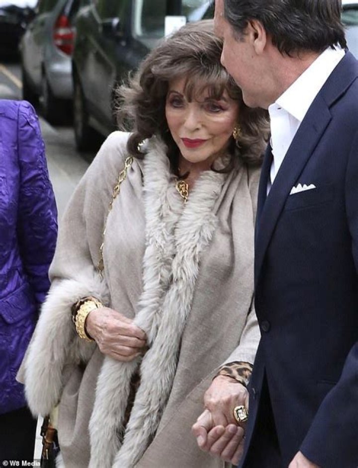 Joan Collins looks chic in a leopard print dress as she celebrates her