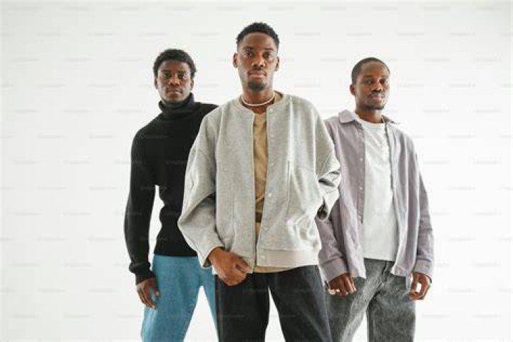 three men standing next to each other in front of a group of people
